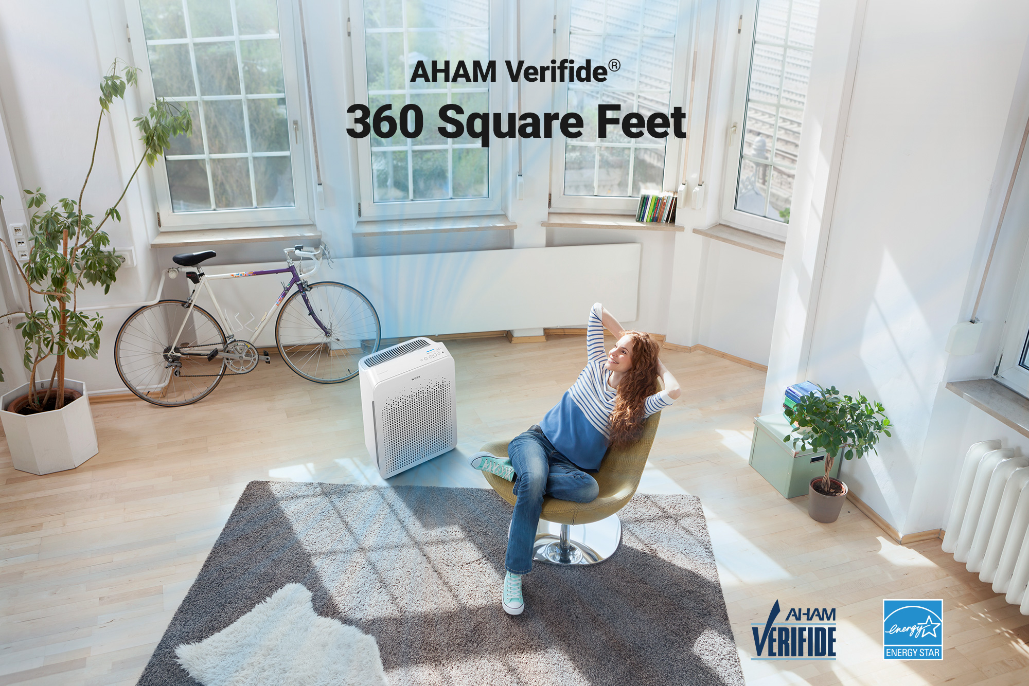 C545 air purifier on floor next to woman sitting in living room and text saying AHAM Verified for 360 Square Feet