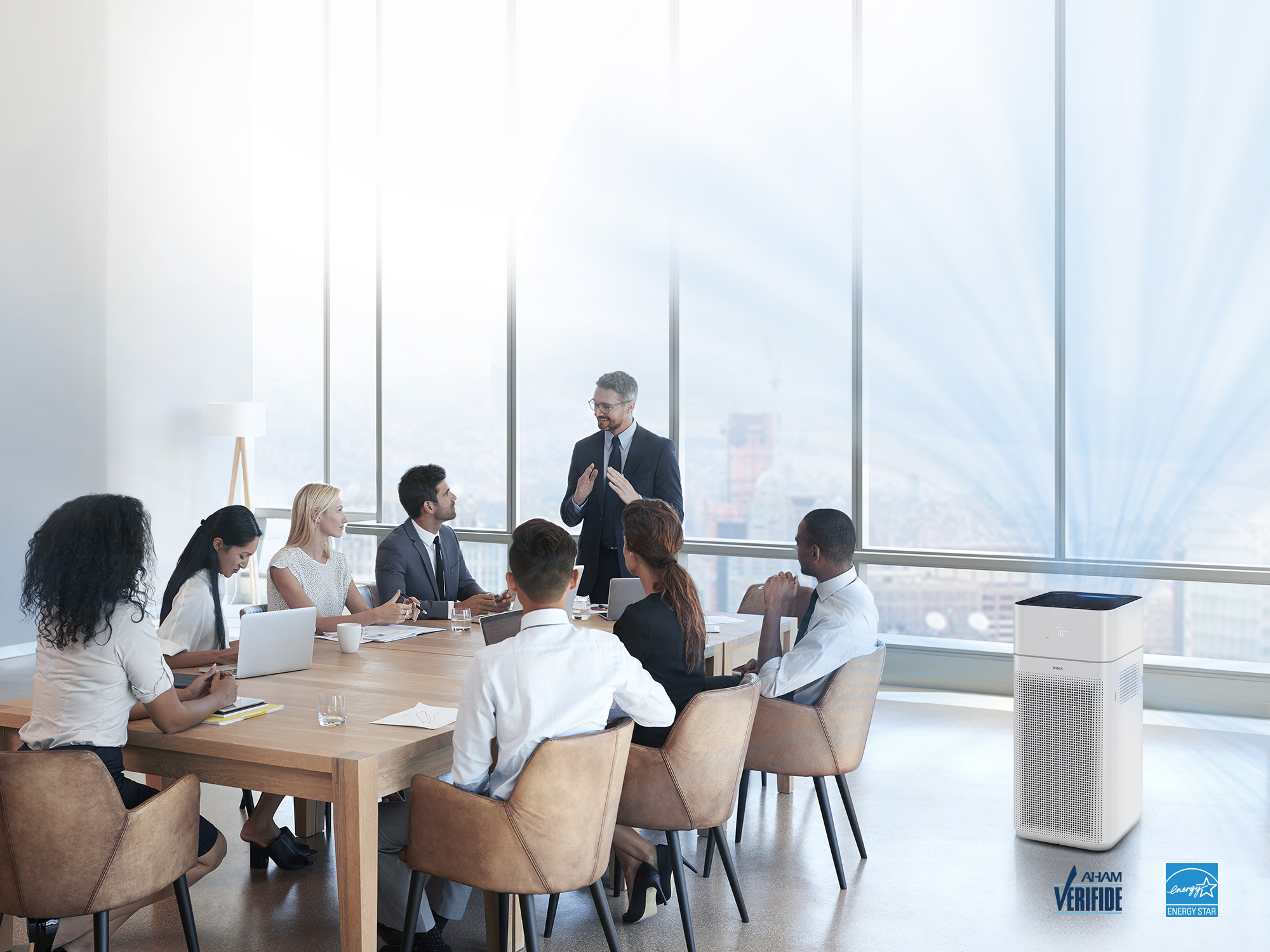 XQ air purifier in an office meeting setting with AHAM verified logo and energy star logo in bottom corner of image