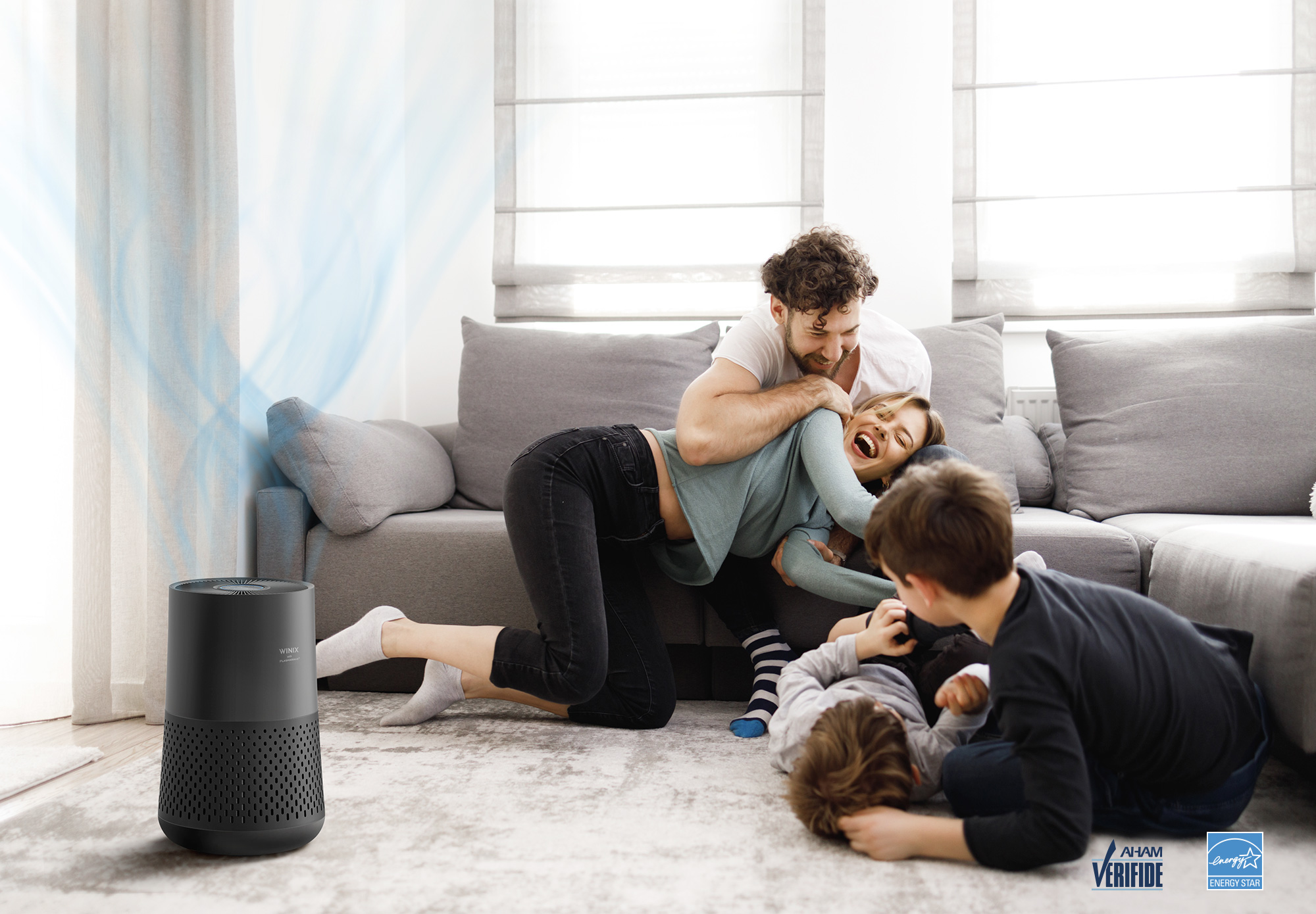A230 Air Purifier on floor next to two parents playing with two children with AHAM verified logo and energy star logo