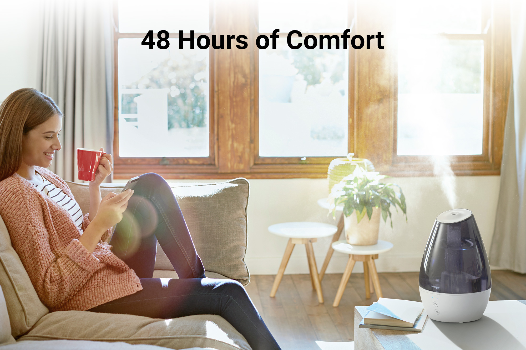 L100 Humidifier on coffee table next to woman sitting on a couch and text saying 48 hours of comfort
