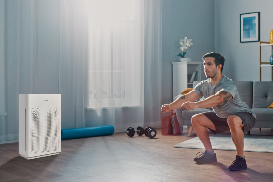 Man exercising at home with AM90 Air Purifier