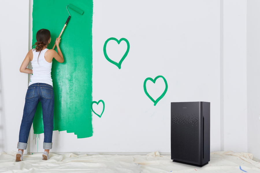 Woman painting indoor wall green with AM80 in corner