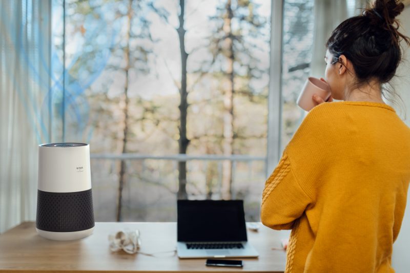 Woman sipping coffee with A231 Air purifier on desk